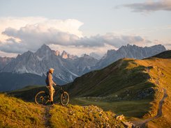 3 Peaks Dolomites © Elias Ochner - Stefan Schwabl Mountain biker on trail overlooking Dolomites at sunset