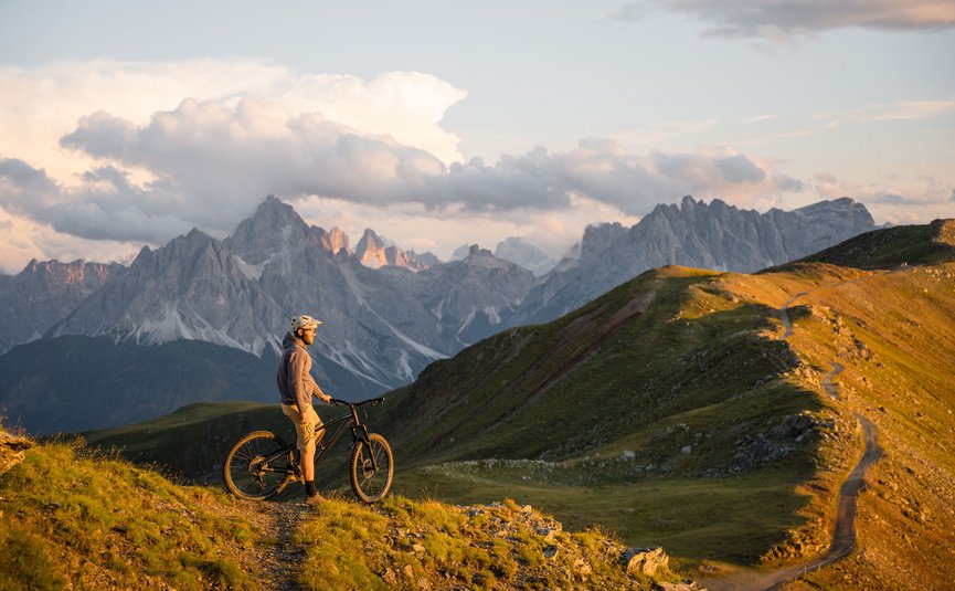 Mountain bike holidays in the 3 Zinnen Dolomites region © Elias Ochner - Stefan Schwabl Mountain biker on trail overlooking Dolomites at sunset