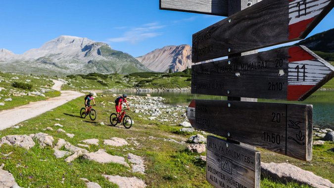 Mountain Bike Holidays © Norman Bielig Zwei Radfahrer auf Bergweg bei Wegweiser in den Dolomiten