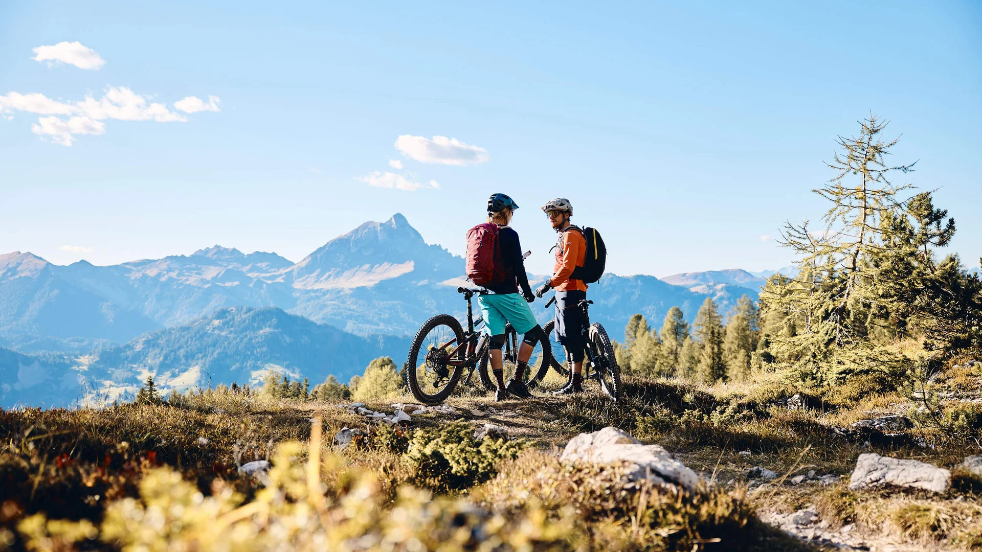Destinations © Tobias Köhler Two mountain bikers with bikes standing in the mountains under clear sky