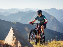Bregenzerwald © Bregenzerwald Tourismus - Sebastian Stiphout Woman mountain biking in the mountains on a sunny day wearing helmet and sunglasses