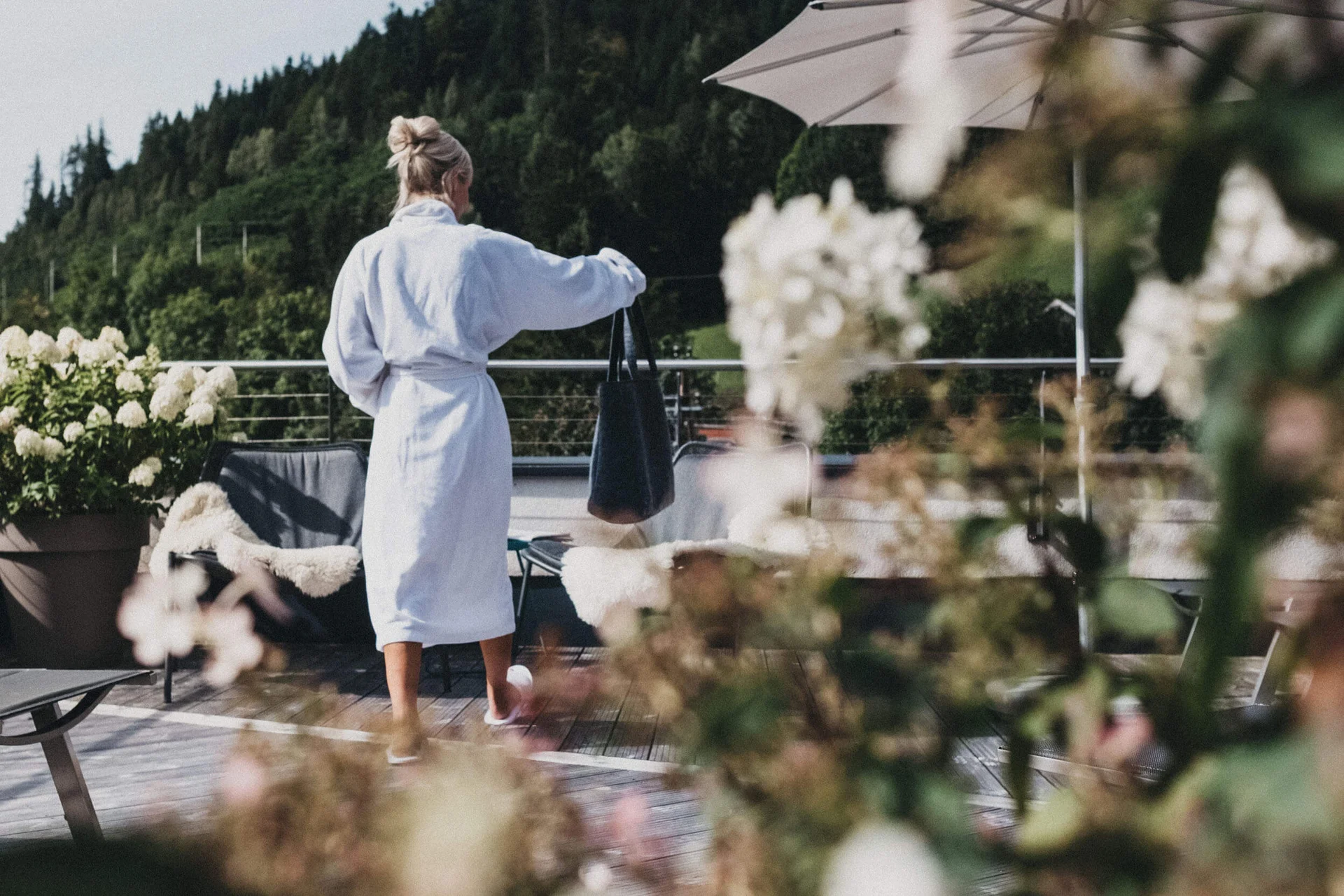 Mountain Bike Holidays © Biohotel Rupertus Frau im Bademantel auf Terrasse mit Blumen und Bergen im Hintergrund