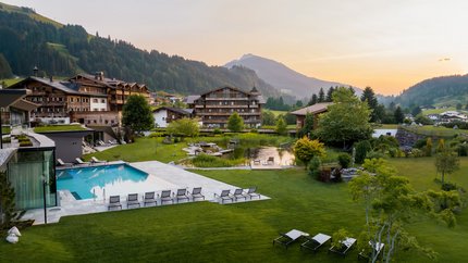 Puradies © creatingclick Bergresort mit Pool, Liegestühlen und grüner Landschaft im Sonnenuntergang