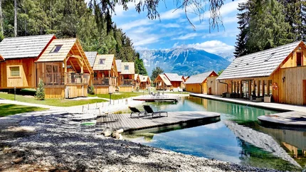 Hotel & Glamping Ribno Alpine Resort © Ribno Alpine Resort - Katarina Strgar Holzhütten am See mit Bergblick und zwei Liegestühlen am Steg