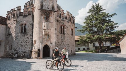 Bressanone © Brixen Tourismus - Hannes Engl Two cyclists in front of a historic stone tower on a sunny day