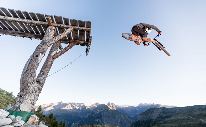Mountain bike holidays in Livigno © Samuel Confortola Mountain biker jumping off wooden ramp in mountain landscape
