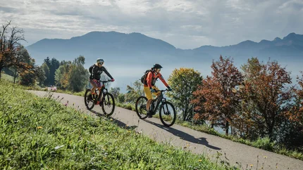 Upper Austria © Salzkammergut Tourismus - Katrin Kerschbaumer Two cyclists riding on a path in a mountainous autumn landscape with lake and trees