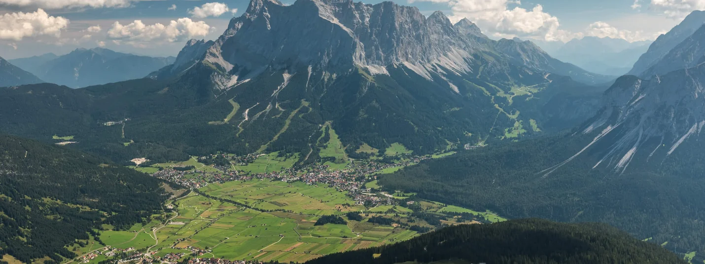 BIKE TRAIL TIROL STAGE EHRWALD - SCHARNITZ © Hotel Ehrwalderhof View over green valley with mountain village and towering mountains in the background