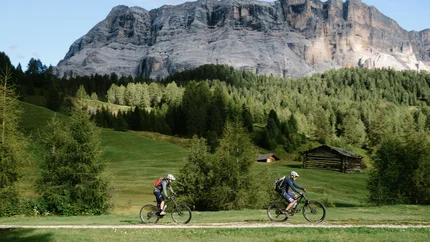 ARMENTARA TOUR © Szymon Bike Two mountain bikers riding on a forest trail with mountains and green trees
