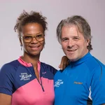 Mountain Bike Holidays © WOM Medien Zwei Personen in bunten Mountainbike-Shirts lächelnd vor grauem Hintergrund