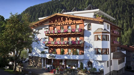 Alpen-Comfort-Hotel Central Hotel mit blumengeschmückten Balkonen vor bewaldetem Bergkulisse