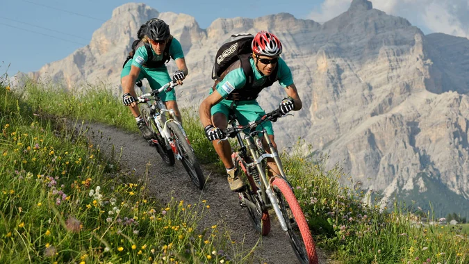 Mountain Bike Holidays © Hotel Melodia del Bosco Zwei Mountainbiker fahren auf einem Bergpfad vor Felsen