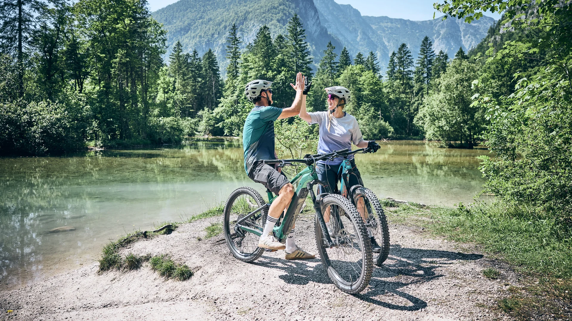 Mountain Bike Holidays © Tobias Köhler Zwei Radfahrer geben sich am See in den Bergen ein Highfive