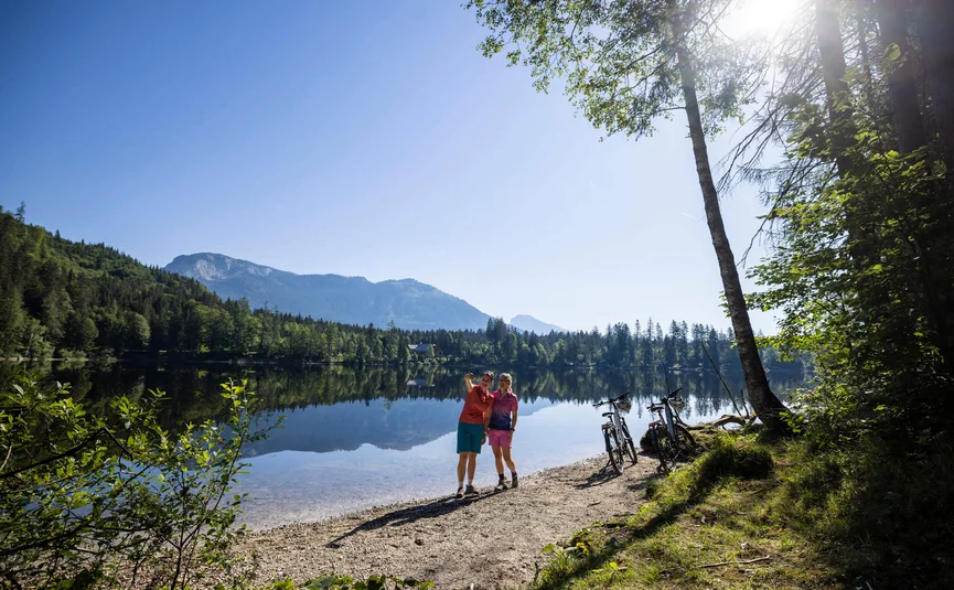Mountain bike holidays in Styria © Velontour Two cyclists taking a selfie by the lake with mountains in the background