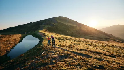 Hacklberg Trail © Tobias Köhler Two mountain bikers riding on a mountain trail at sunset