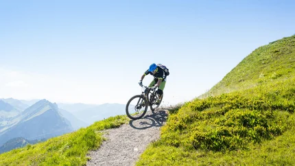 Au - Schoppernau - Around the Kanisfluh © Stephan Schatz Mountain biker riding on a steep mountain trail with green grass
