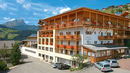 Hotel Pider © Hotel Pider Gasthof mit roten Blumen und Bergen im Hintergrund bei klarem Himmel