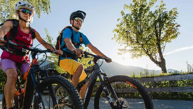 Mountain Bike Holidays © Salzkammergut Tourismus - Katrin Kerschbaumer Zwei Radfahrer mit Schutzhelm fahren auf Landstraße bei sonnigem Wetter