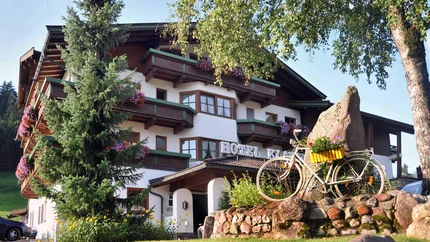 Bikehotel Klausen © Andreas Hauser Hotel mit Balkonblumen, Fahrrad und Felsen im Garten