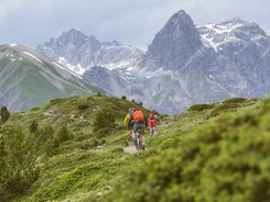 Livigno © Hansi Heckmair Cyclists riding on a mountain trail with tall mountains in the background
