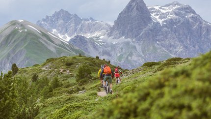 Livigno © Hansi Heckmair Cyclists riding on a mountain trail with tall mountains in the background