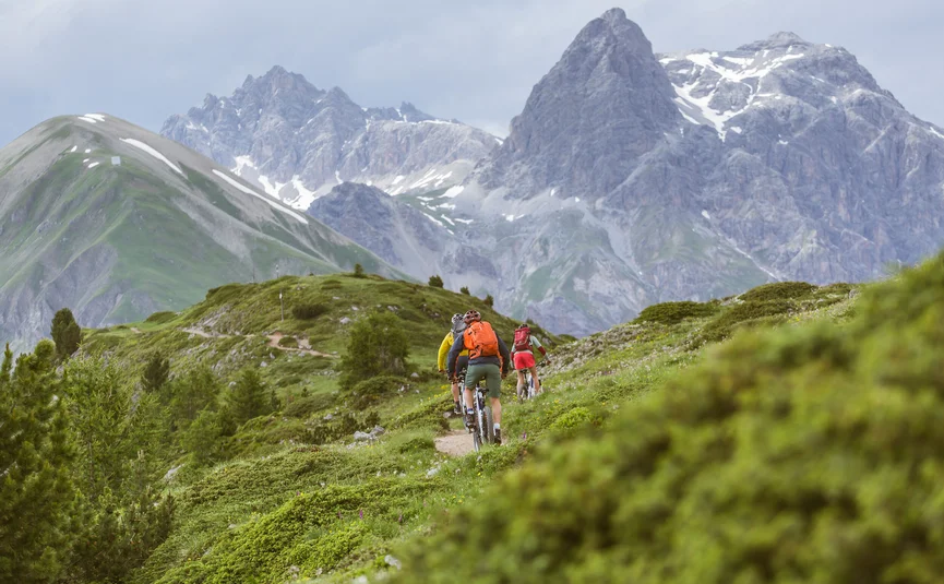 Mountain bike holidays in Livigno © Hansi Heckmair Cyclists riding on a mountain trail with tall mountains in the background