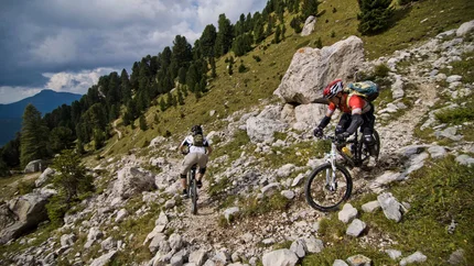LATEMAR CIRCUIT © Exploring GmbH Two mountain bikers ride on a rocky mountain trail with green trees