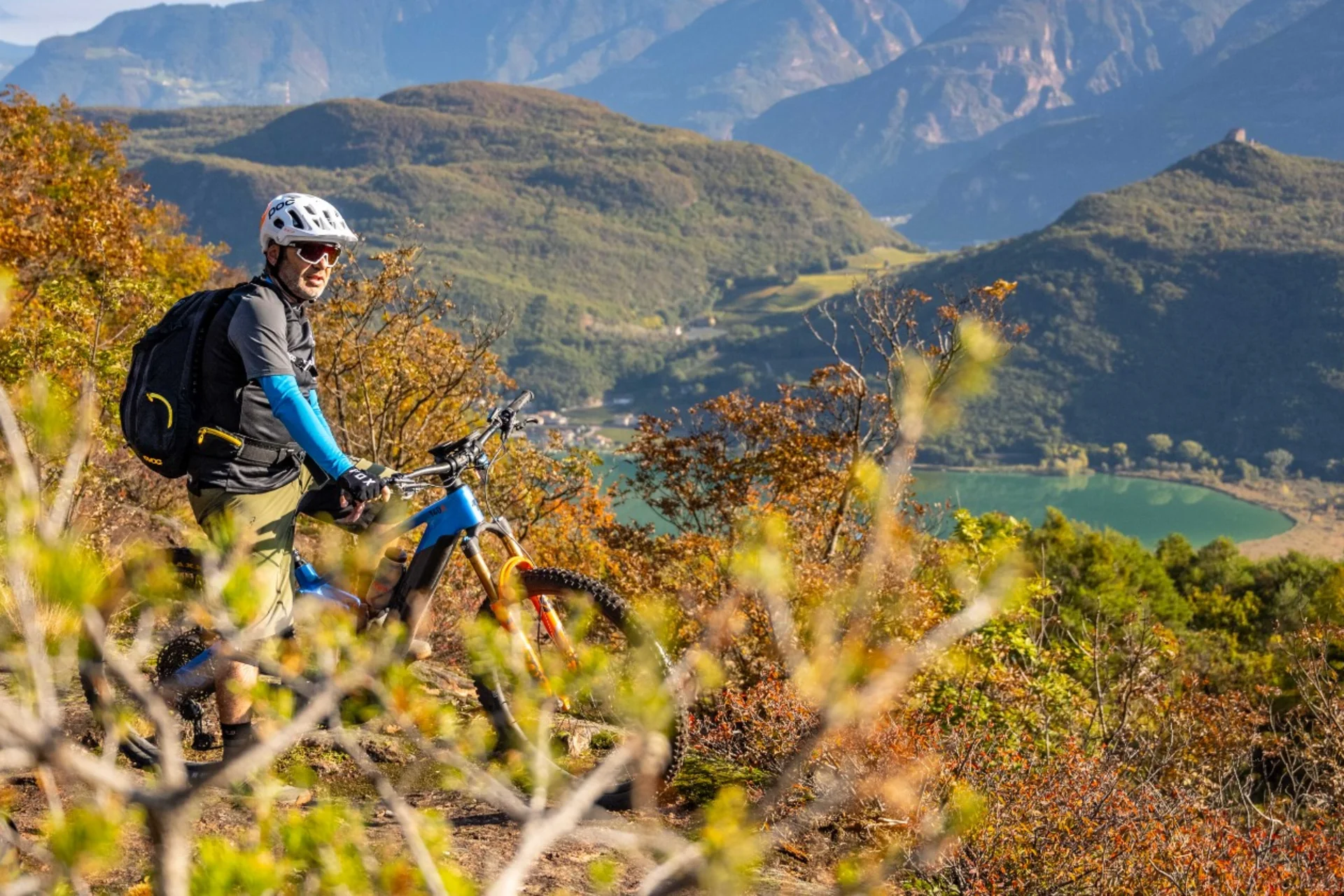 Mountain Bike Holidays © Antie Braito Mountainbiker mit Helm auf einem Hügel mit Berg- und Seeblick