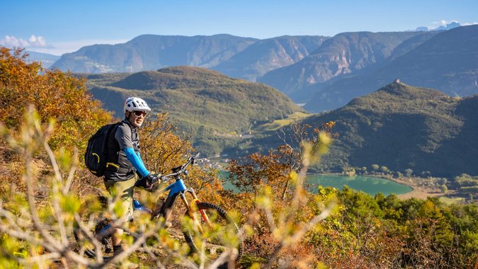 Mountain Bike Holidays © Antie Braito Mountainbiker mit Helm auf einem Hügel mit Berg- und Seeblick
