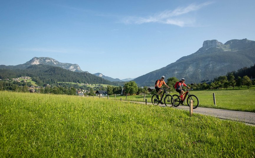 Mountain bike holidays in Styria © Erwin Haiden - bikeboard.at Two cyclists riding on a path through green fields with mountains in the background