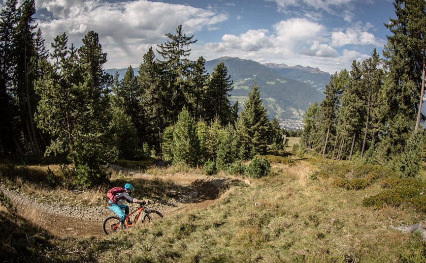 Mountain bike holiday in Brixen © Dennis Stratmann Mountain biker rides on a forest trail in the mountains under cloudy sky