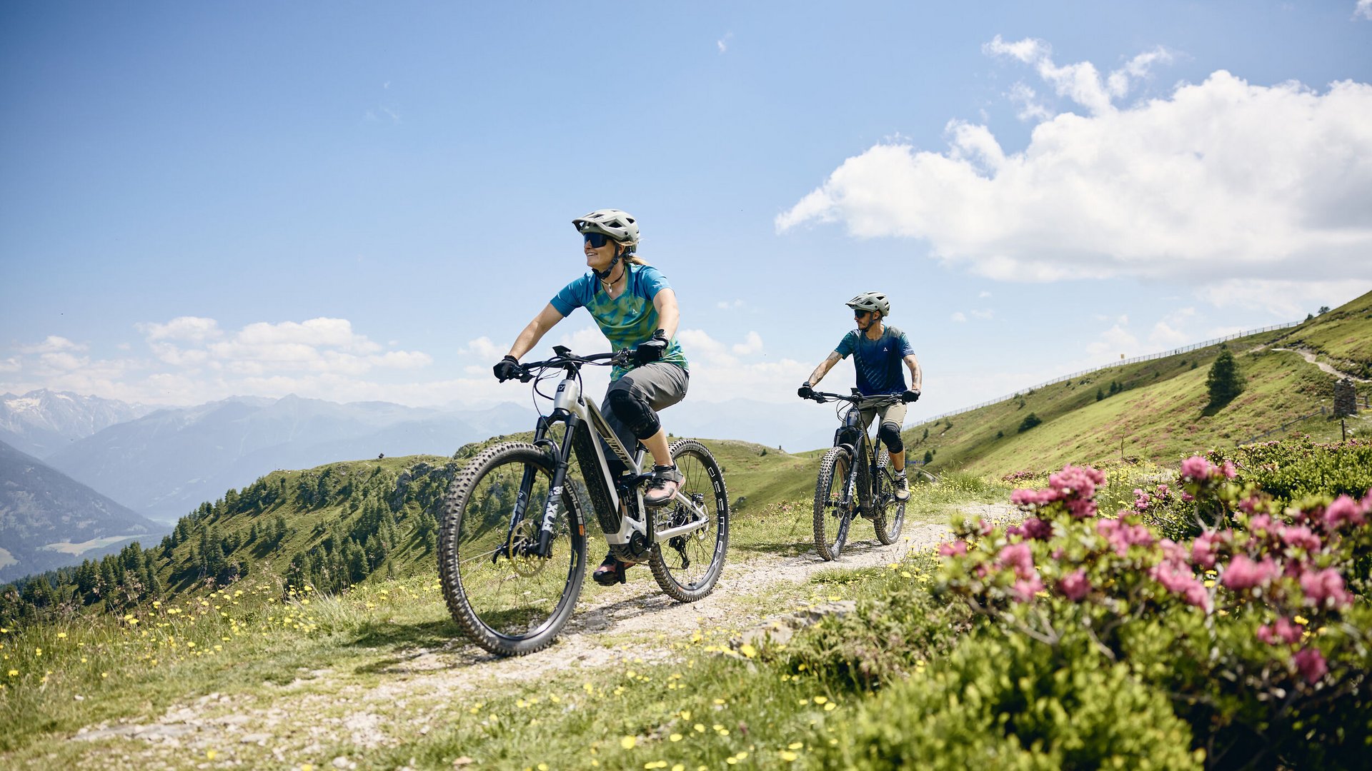 South Tyrol © Tobias Köhler Two people riding e-mountain bikes on a mountain trail on a sunny day