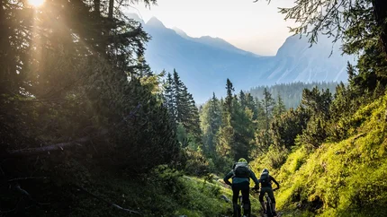 FROM SCHÖNRUH OVER THE THÖRLEN TO LAKE EIBSEE © Norman Bielig Two mountain bikers riding on a forest trail in the mountains during sunlight
