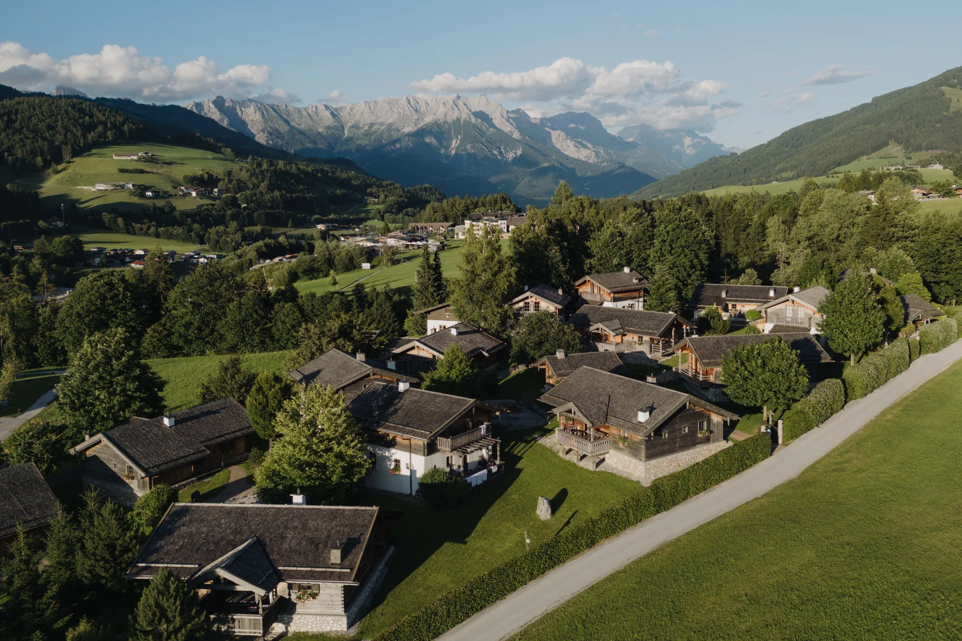 Mountain Bike Holidays © Lukas Reschreiter Dorf mit Holzhäusern und Bergen im Hintergrund bei sonnigem Wetter