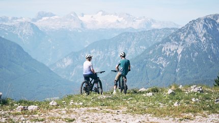 Ausseerland Salzkammergut © Tobias Köhler Two cyclists wearing helmets overlooking mountains with snow in the background