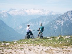 Ausseerland Salzkammergut © Tobias Köhler Two cyclists wearing helmets overlooking mountains with snow in the background
