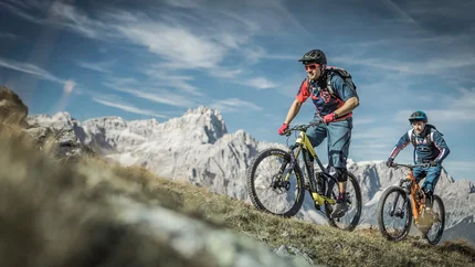 ALP TOUR CLASSIC © Manuel Kottersteger Two mountain bikers riding uphill with mountains and blue sky in background
