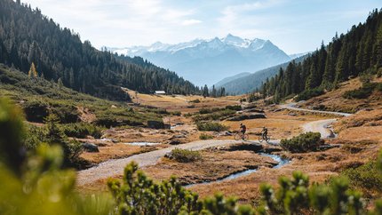 Kitzbühel Alps - Brixental Valley © TVB Kitzbüheler Alpen - Brixental - Mathäus Gartner Two cyclists on a mountain trail with snow-capped peaks in the background