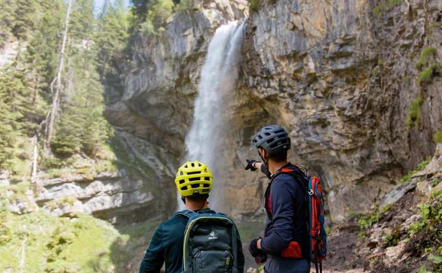 Mountain bike holidays in Flachau © David Karg Two cyclists with helmets looking at a waterfall in rocky terrain