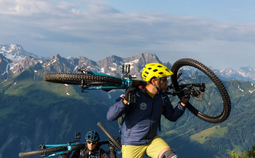 Diedamskopftrail © David Karg Two mountain bikers carrying their bikes in the mountains