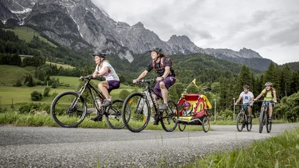 Alpine pastures - Sinnlehenalm © Artisual Family cycling with child in trailer on a mountain road