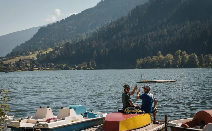 Mountain Bike holidays in the Weissensee region © David Karg Two men on dock drinking beer with lake and mountains behind