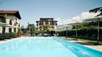 Traminerhof | good life. cool ride. © Manuel Ferrigato Outdoor swimming pool with loungers and umbrellas in front of a hotel building