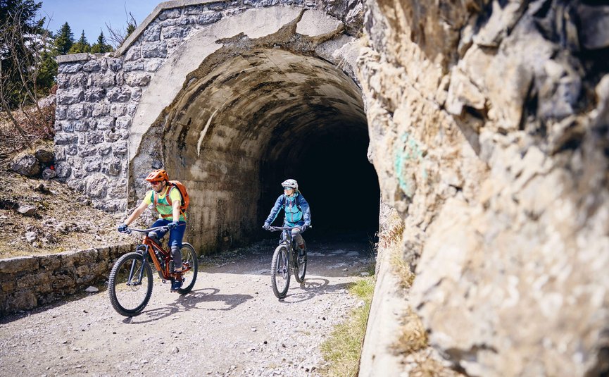 Mountain biking in Lombardy © Tobias Köhler Two cyclists emerging from a stone tunnel on a mountain trail
