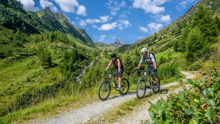 PAZNAUN VALLEY TOUR © TVB Paznaun Ischgl Two mountain bikers on a trail in green mountains on a sunny day
