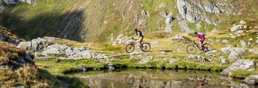 Flachau © Flachau Tourismus - Geri Oberreiter Two mountain bikers riding past a mountain lake in the Alps