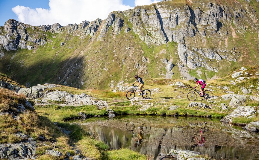 Mountain bike holidays in Flachau © Flachau Tourismus - Geri Oberreiter Two mountain bikers riding past a mountain lake in the Alps