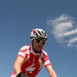 Mountain Bike Holidays © AlpenParks Hagan Lodge Altaussee Radfahrer fährt auf Mountainbike vor Holzhäusern auf Grasland