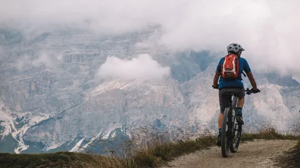 TO THE PISCIADÙ WATERFALLS © Szymon Bike Mountain biker riding on trail with foggy mountains in background