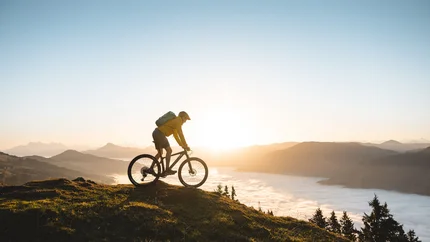 Tyrol © TVB Kitzbüheler Alpen Brixental - Mathäus Gartner Mountain biker at sunrise on a hill with fog in the valley
